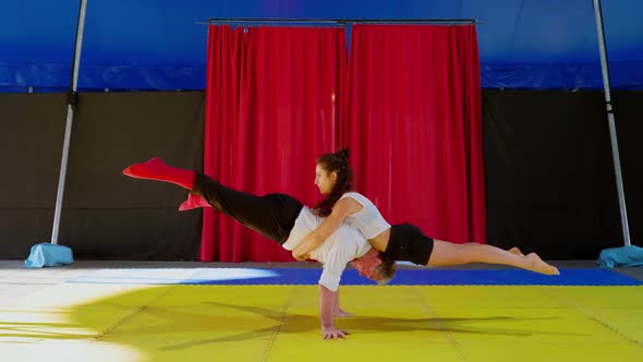 Acrobats in circus performing seesaw counterbalance trick alt