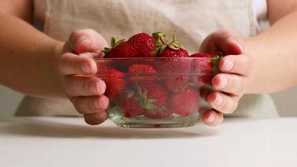 Girl Hands Puts a Glass Plate with Strawberries and Berries on a White Table
