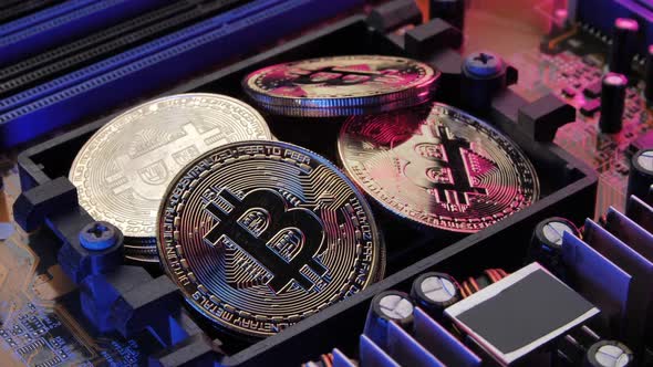 Golden coins with bitcoin symbol on electronic circuits in a computer mainboard. alt