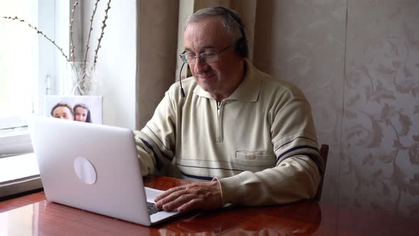 Smiling Senior Man Wear Earphones Wave to Camera Having Video Call on Laptop Happy Elderly Male in alt
