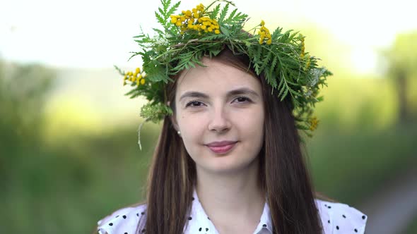 Portrait of a Woman in a Wreath of Wild Flowers Looking at the Camera