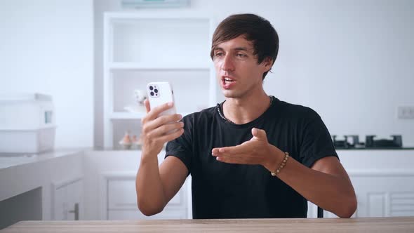 Young Man Holding Smartphone and Talking on a Video Call Using His Mobile Phone at Home in the