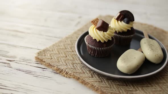 Hand picks up muffin from tray. Muffins and cupcakes, cookie ice creams on stick alt