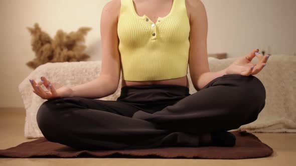 A Woman Without a Face Sits in a Yoga Pose