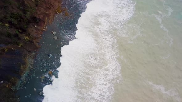 Aerial shot of Big Sur beach waves & slow reveal of RV parked off foggy road perched on huge cliffs alt