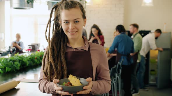 Portrait of Pretty Girl Standing in Cooking School with Delicious Dish Smiling alt