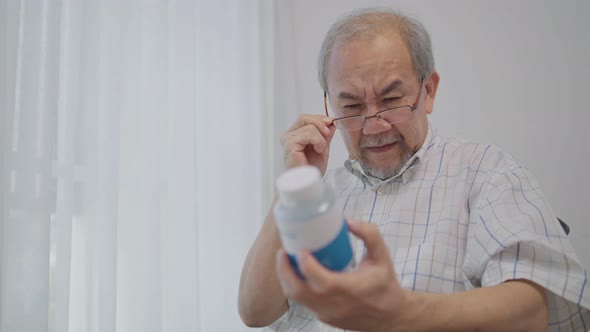 Asian senior man with farsighted reading prescription on medicine bottle