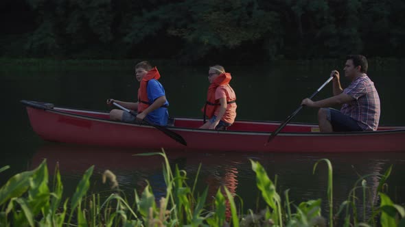 Kids at summer camp paddling canoe in pond