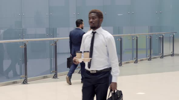 Businesspeople going along glass fence inside office center