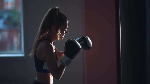 White Female Athlete Boxing the Punching Bag in Urban Industrial Gym alt