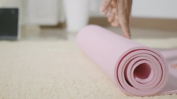woman rolling fitness yoga pink mat before sports practice for exercise alt