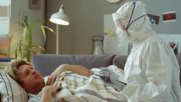 Doctor in Protective Suit Visiting Sick Man at Home alt
