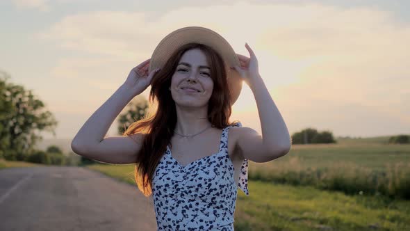 Beautiful Ginger Woman Puts on a Straw Hat and Playfully Smiles Outdoor alt