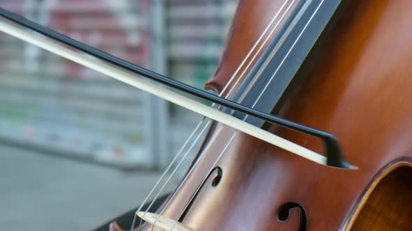 Young man is playing his cello at street as a close-up slow-motion view