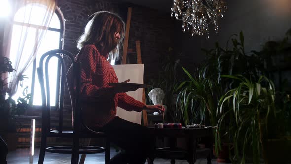 A Young Pretty Woman Walks in the Art Workshop and Starts Mixing Shades on a Palette alt