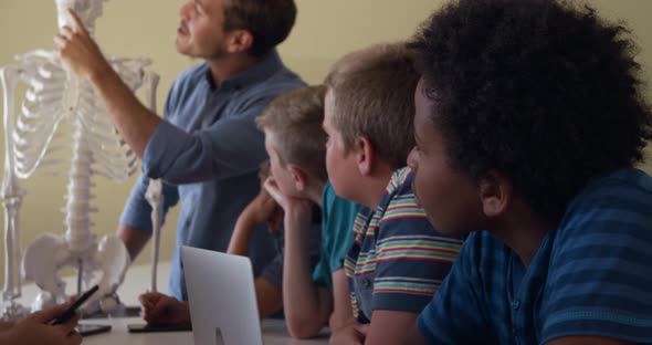 Male teacher with human skeleton model teaching in the class alt