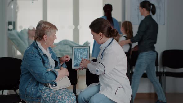 Close Up of Doctor and Pensioner Looking at x Ray Scan on Digital Tablet alt