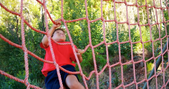 Determined boy climbing a net during obstacle course alt