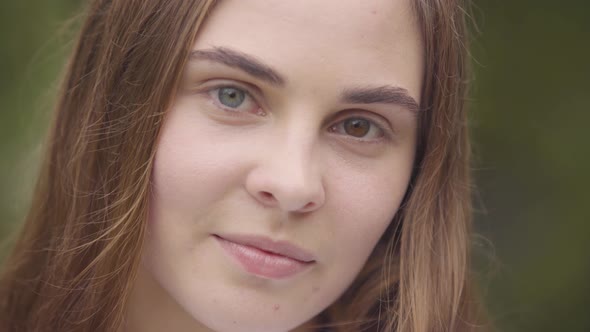 Close-up Portrait of Pretty Carefree Young Woman with Different Colored Eyes Looking at Camera alt