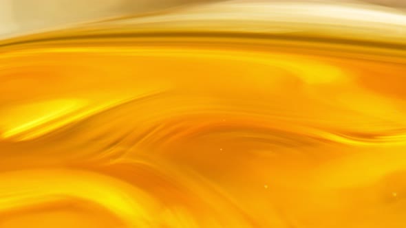 Super Slow Motion Shot of Moving Oil Waves on Golden Background at 1000Fps alt