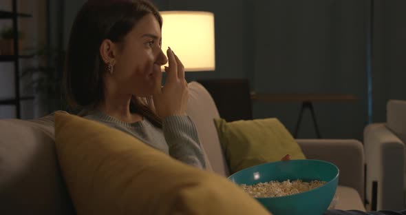 Teenager eating popcorn and watching TV