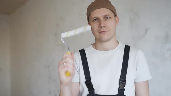 Man Construction Overalls Happily Shows Paint Roller To Camera alt