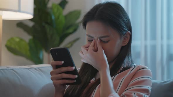 Exhausted Asian young woman hurt eye while using mobile phone at night. alt