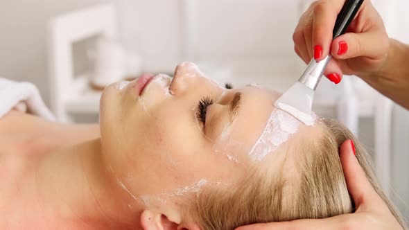 Beautician cosmetologist cleans removes face peeling beauty mask. alt