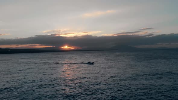 Flying over a boat on a calm ocean and beautiful  sunset near the island of Haiti