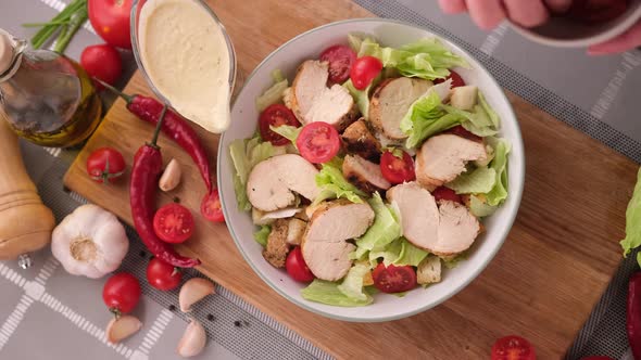 Cooking Caesar Salad Inside Deep Cooking Bowl  Adding Sliced Cherry Tomatoes alt