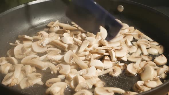 Add Sliced Fresh Champinton Mushrooms to a Hot Frying Pan with Oil and Fry Stirring with a Silicone