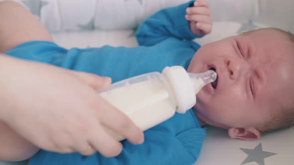 Mommy Feeds Little Child with Milk Mix in Comfortable Cocoon alt