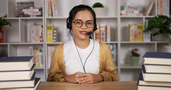 Happy female student in headphones and glasses talking at camera alt