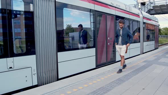 Casual Man Walking Next To Train On Platform