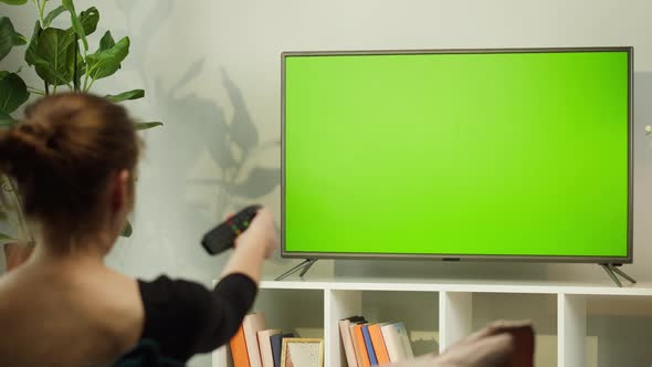 Woman Watching TV with Green Screen in Living Room Back View alt