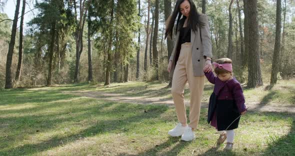 Happy Little Girl Walking and Playing with Mother Among Trees in Coniferous Forest, Healthy Child alt