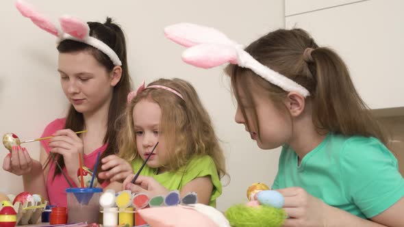 Three Cute Girls are Preparing for the Easter Holiday and Painting Chicken Eggs