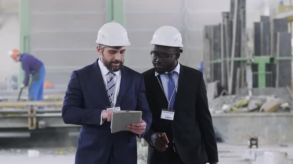 Factory manager going through manufactory with foreign colleague