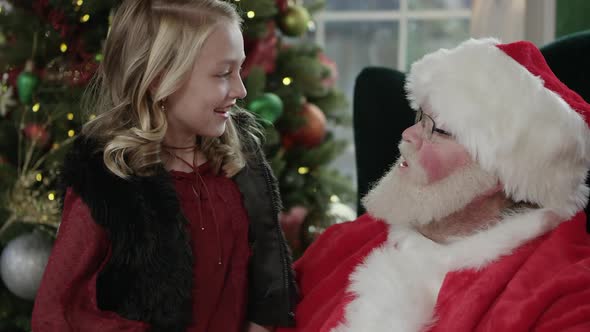 Young girl smiling as she sits on Santa's lap alt