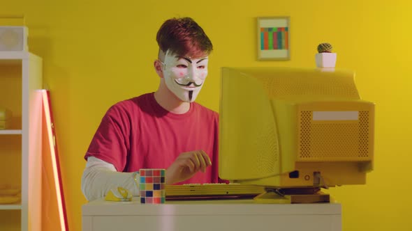 Man In Hacker Mask Is Working at Computer