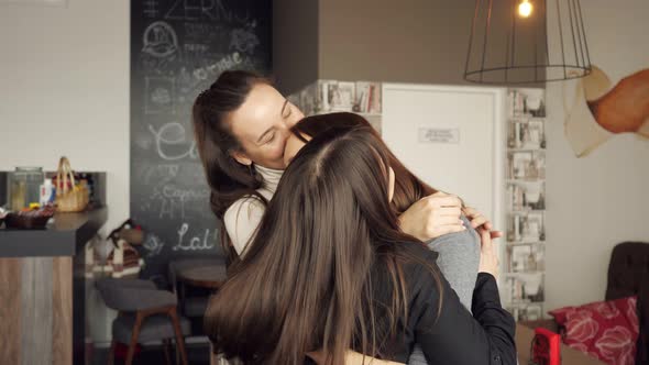 Three Women Friends Are Hugging Together Greeting. Friendly Meeting in Cafe. alt
