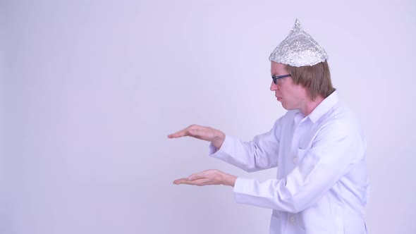 Young Man Doctor with Tinfoil Hat Shaking While Showing Something alt
