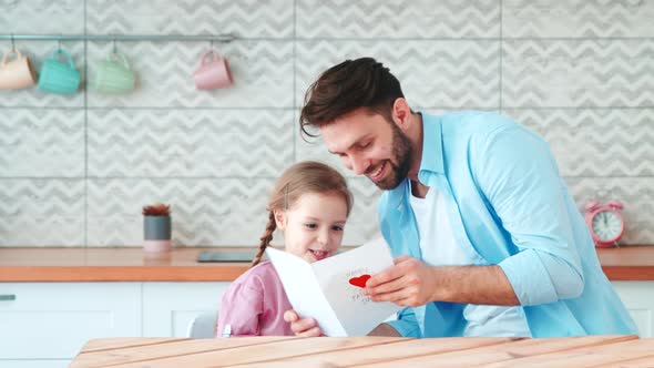 Little preschool girl giving her father a handmade card alt