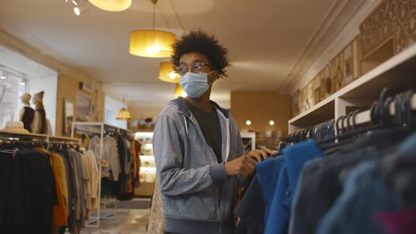 African Young Man Stealing Jeans While Being in Clothes Shop alt