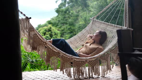 A woman lying and relaxing on hammock while looking at green nature