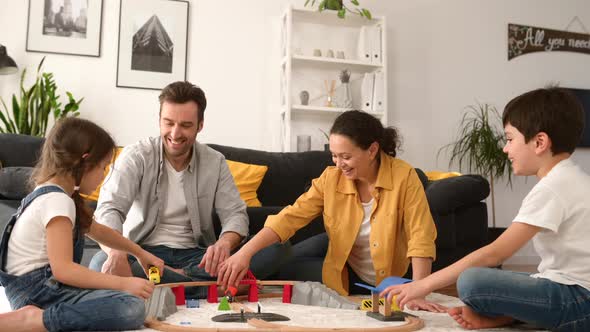 Lovely Family of Four Sitting on Floor in Cozy Living Room and Playing