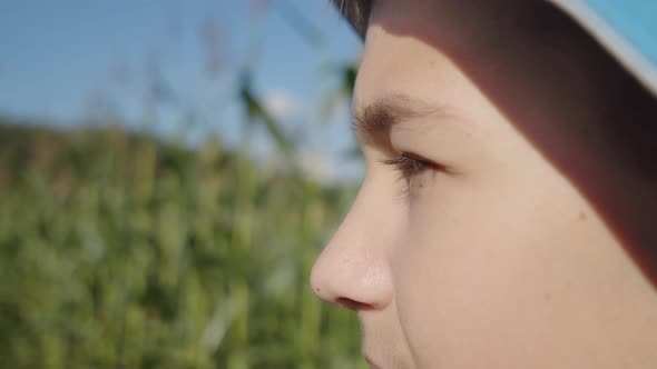 Profile of a Serious Boy in a Hat Standing Outdoors and Looking alt