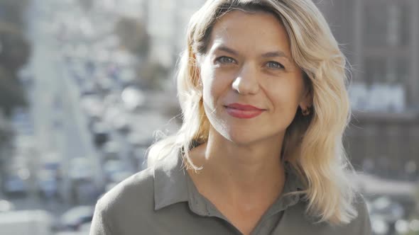 Beautiful Mature Woman Smiling To the Camera on City Background alt