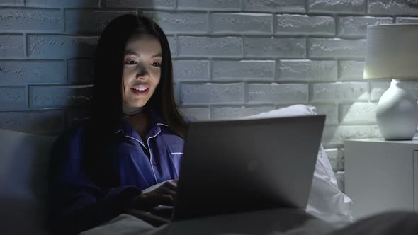 Happy Woman Finishing Project on Laptop at Night, Lying in Bed, Working Overtime alt