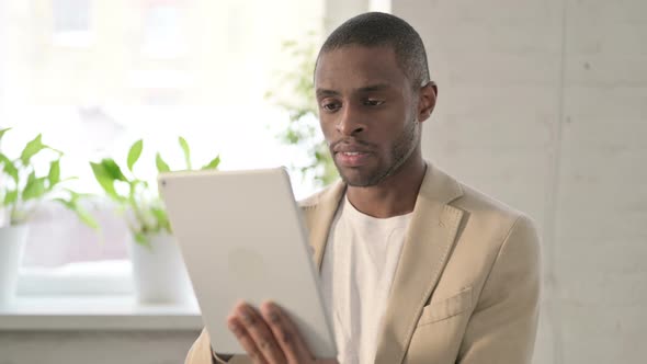 Portrait of African Man Celebrating on Tablet in Office alt